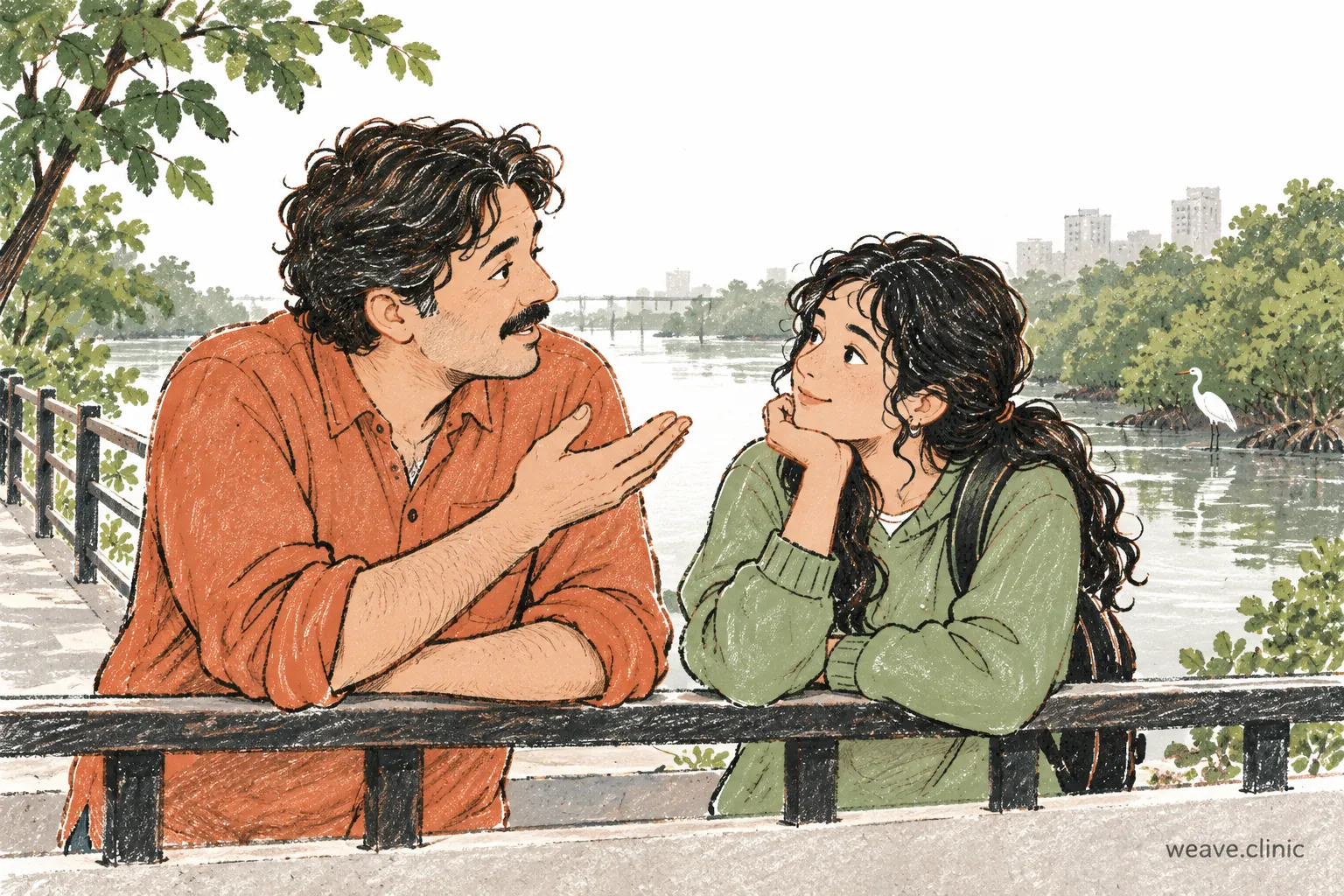 Two adults talking beside a creek and mangroves.